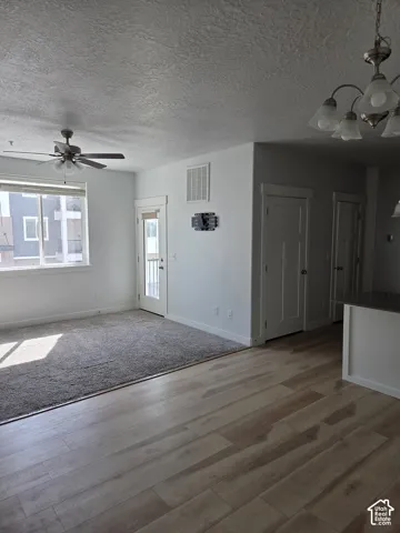 Open concept living area featuring wood-finish flooring, a ceiling fan, and a large window