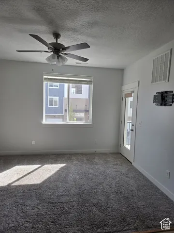 Room featuring textured carpeting, white walls, and a ceiling fan with integrated lighting