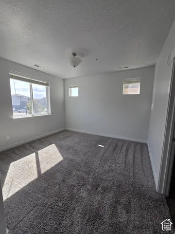 Spacious room featuring neutral grey walls and plush grey carpet