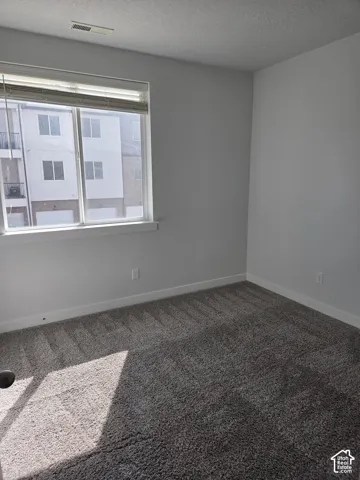 Bright interior space featuring a large window, neutral wall paint, and plush carpeting