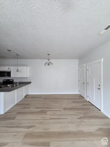 Open concept living area featuring light wood-finish flooring, white walls, and a textured ceiling