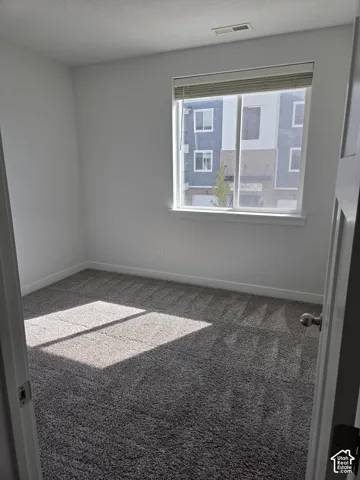 Carpeted room featuring a single window with blinds, white walls, and white trim