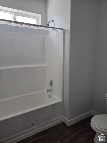 Bathroom featuring a white tub with shower, chrome fixtures, and a high window