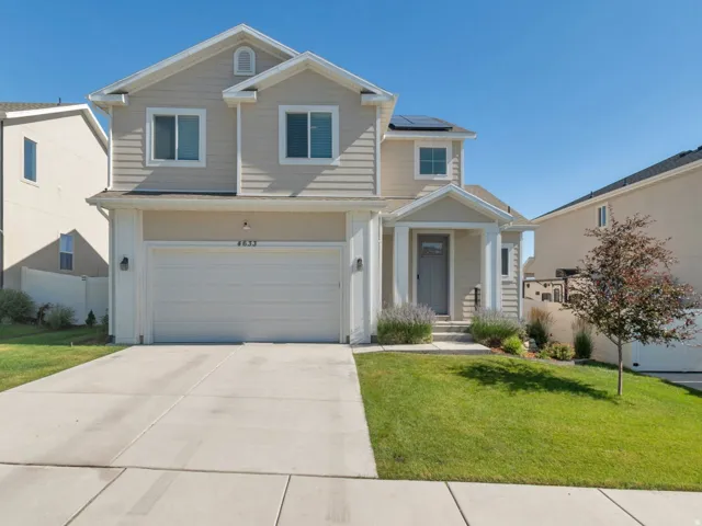 Two-story residence featuring light-colored siding, an attached two-car garage, and a covered front entry