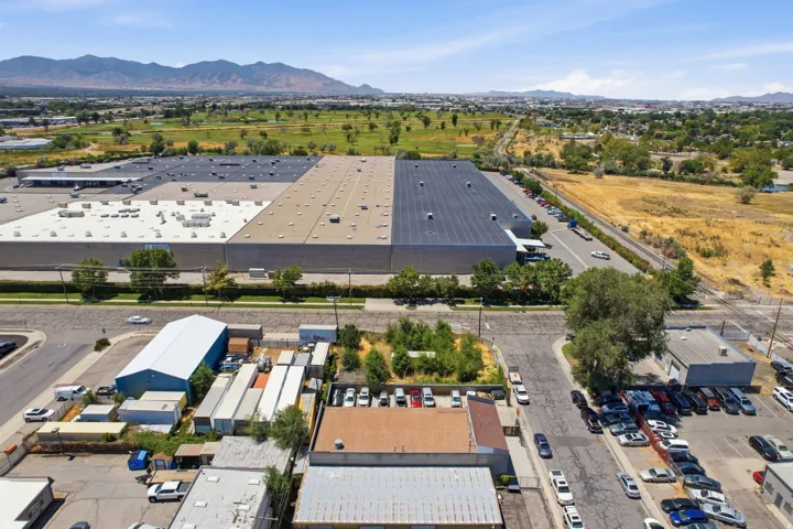 Expansive industrial facility featuring a large, multi-section flat roof, multiple loading dock areas, and an extensive parking area