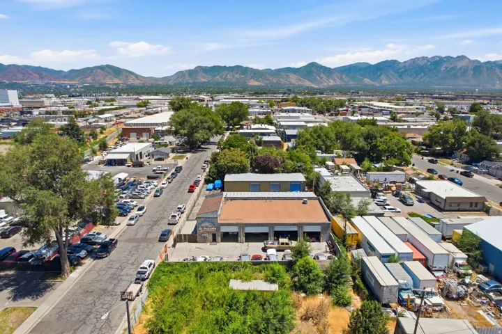 Commercial property featuring a large structure with multiple bay doors, an adjacent undeveloped lot, and a paved street frontage