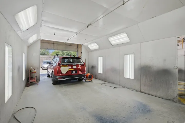 Spacious industrial bay featuring high ceilings, fluorescent lighting, a large roll-up door, concrete flooring, and durable panel walls