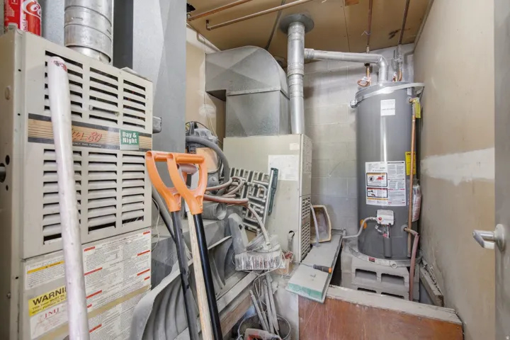 Utility area featuring a water heater and furnace with exposed ductwork and copper piping
