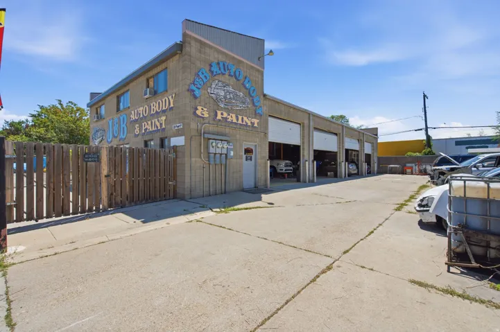 Commercial building featuring a brick facade with signage, multiple bay doors, and a paved lot