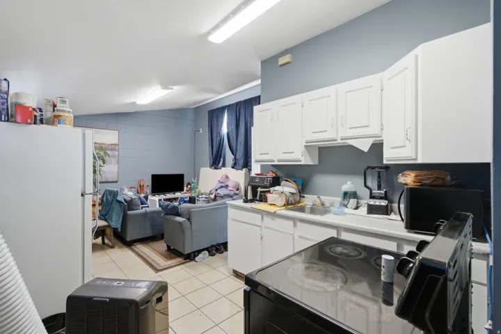 Kitchenette featuring white cabinetry, a white countertop, and a stainless steel sink