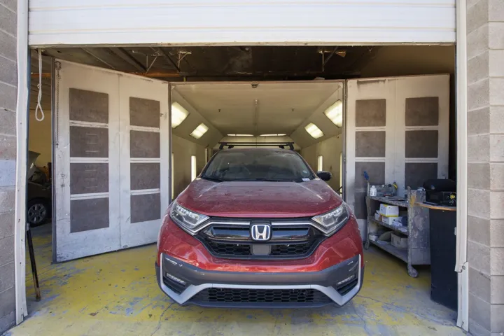 Industrial bay featuring a large roll-up door, concrete block construction, and a dedicated paint booth with integrated lighting