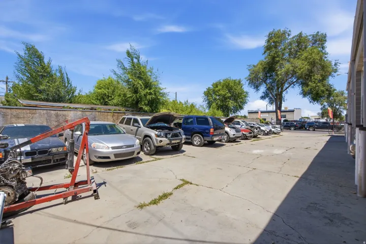 Paved concrete lot with perimeter fencing and mature trees