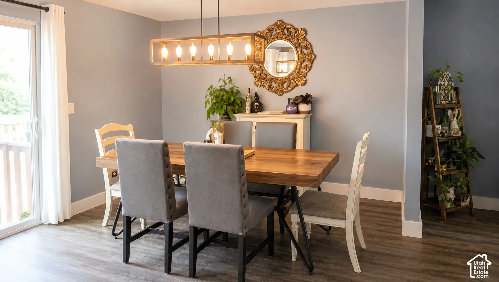 Dining area featuring wood-finish flooring, a contemporary linear chandelier, light blue walls, and a glass sliding door leading to an outdoor space