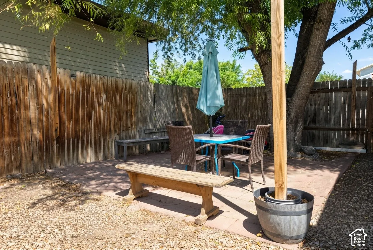 Private outdoor space featuring a paved patio area, mature trees, wood fencing, and gravel landscaping