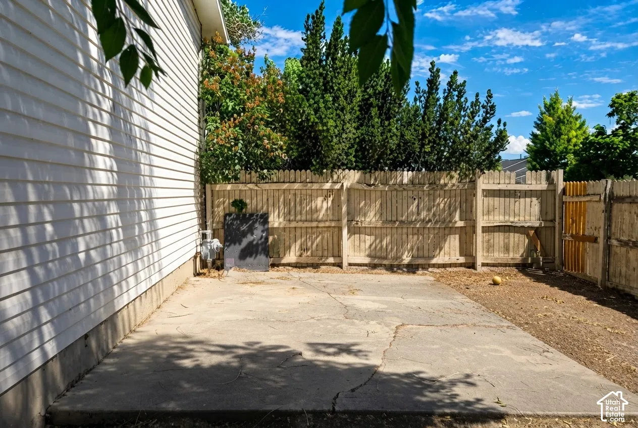 Concrete patio with surrounding wood fencing and mature perimeter foliage