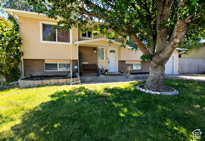 Split-level exterior featuring a combination of cream vertical siding and brick veneer