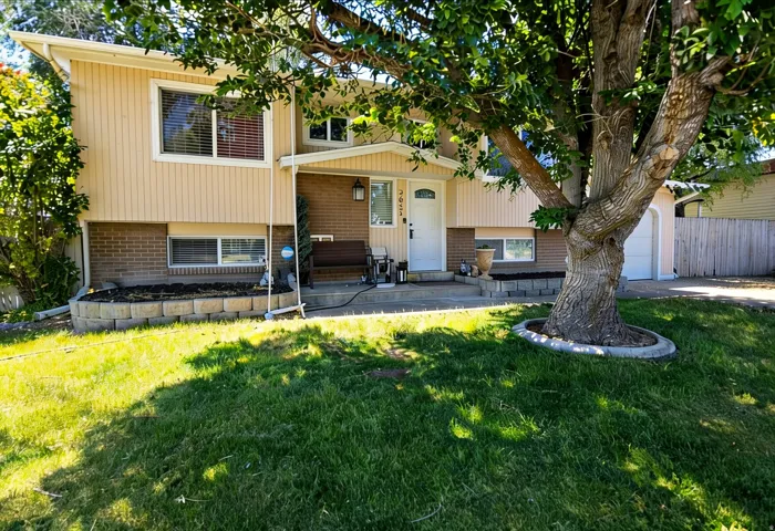 Split-level exterior featuring a combination of cream vertical siding and brick veneer