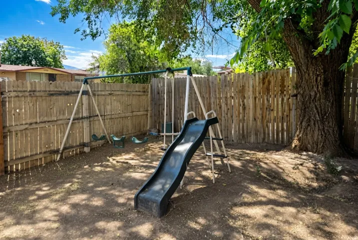Private backyard area featuring a wood plank fence and mature shade trees