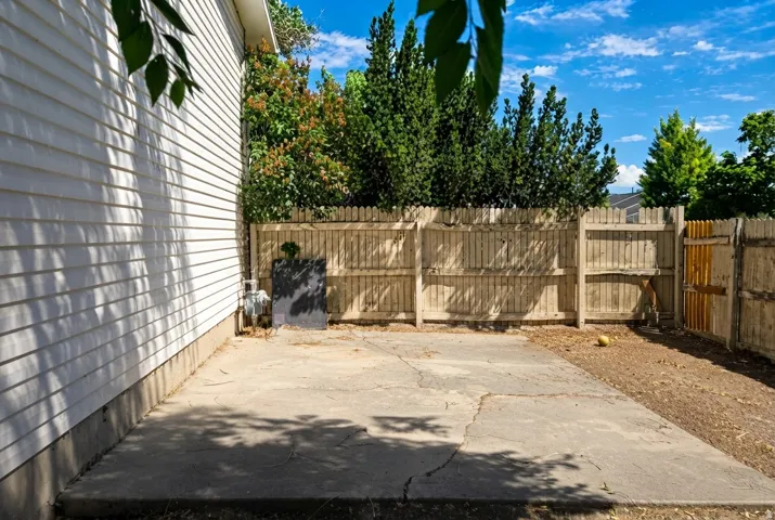 Concrete patio with surrounding wood fencing and mature perimeter foliage