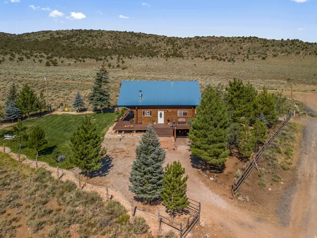 Log cabin exterior with a blue metal roof, an elevated wood deck, and a front entry porch