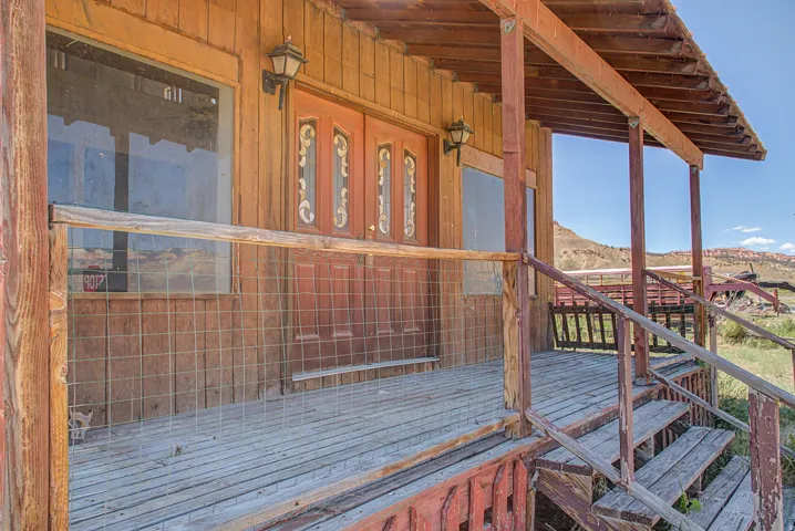 Wood-sided exterior featuring a covered porch, wood plank flooring, and a decorative double entry door with ornate glass inserts