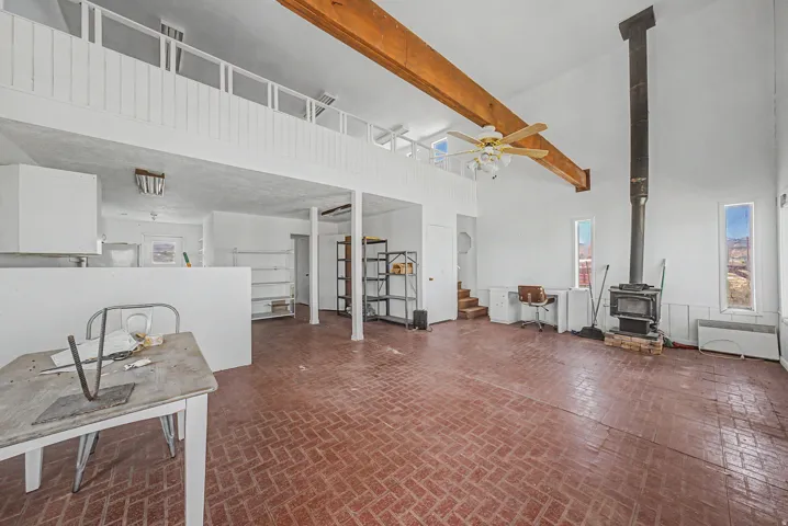 Spacious living area featuring exposed wood beams, vaulted ceilings, and brick-finish flooring