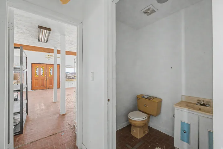 Interior space featuring a red brick-patterned floor, exposed wood beam, and double entry doors with decorative glass panels