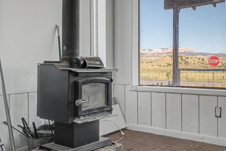 Black metal wood-burning stove with a glass-front door, featuring a stove pipe