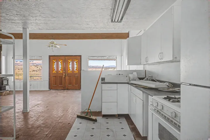 Kitchen area featuring white cabinetry, a white refrigerator, and a white oven
