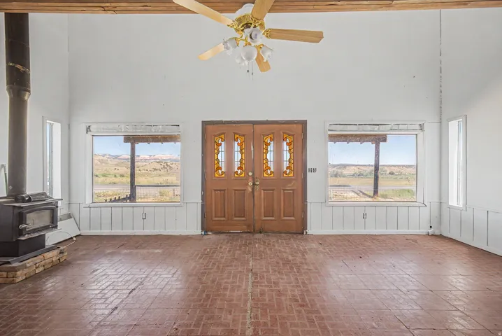 Spacious room featuring exposed wood ceiling beams, a ceiling fan, and brick-pattern flooring
