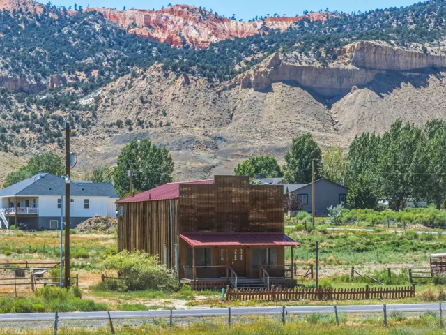 Rustic commercial-style structure featuring vertical wood siding, a red metal roof, and an inviting covered porch