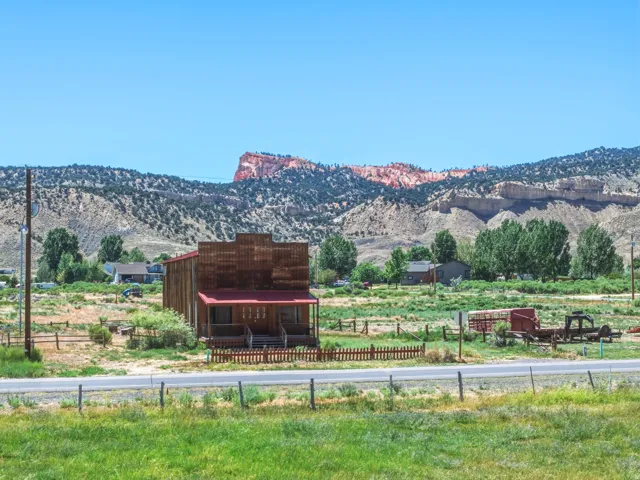 Two-story wood-sided structure featuring a covered porch and a red metal roof
