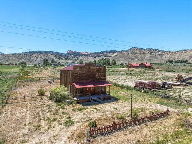 Rustic two-story structure with a covered porch and red metal roofing