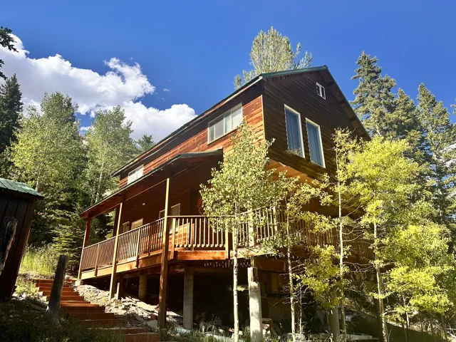 Wood-sided residence featuring a multi-level deck and surrounding mature trees