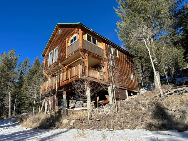 Multi-level cabin-style residence featuring natural wood siding and a green metal roof