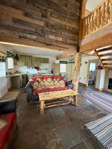 Vaulted ceilings with wood paneling, exposed wood beams, slate tile flooring, and a kitchen featuring painted cabinetry