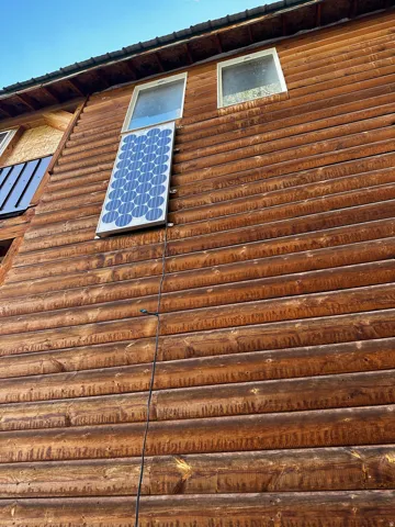 Log cabin style exterior featuring a wall-mounted solar panel