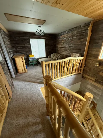 Loft area featuring rustic wood paneled walls and light-toned ceiling paneling
