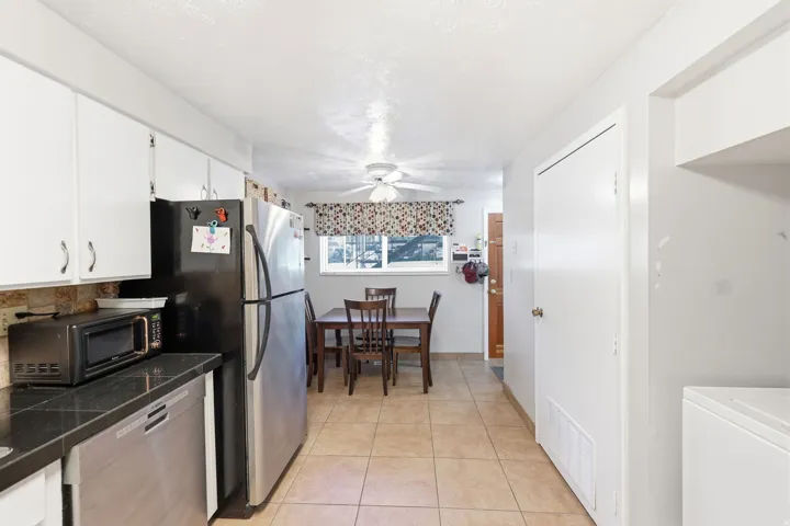 Kitchen featuring tile flooring, white cabinetry, dark countertops, and a window with natural light