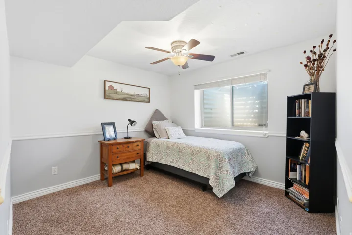 Bedroom featuring wall-to-wall carpeting, a multi-pane window with blinds, and a ceiling fan with integrated lighting