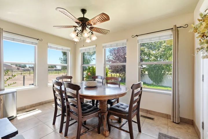 Dining area with multiple windows, tile flooring, and a ceiling fan with integrated lighting