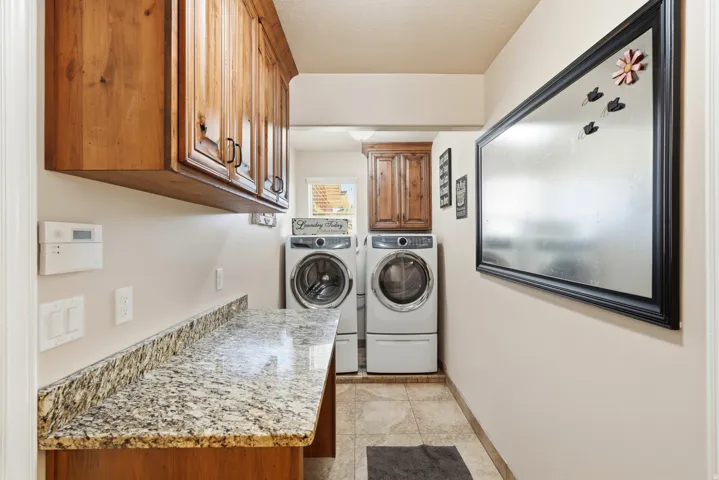 Functional utility space featuring wood cabinetry, a light-toned patterned countertop, and tile flooring