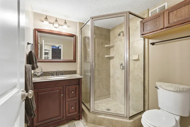 Bathroom featuring a dark wood vanity with a granite-style countertop, undermount sink, and framed mirror