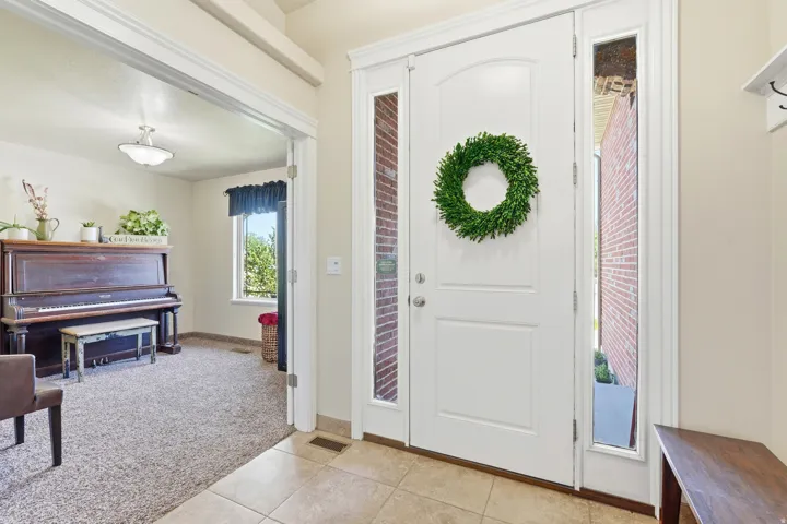 Entryway with tiled flooring and a white front door featuring an arched panel and sidelights