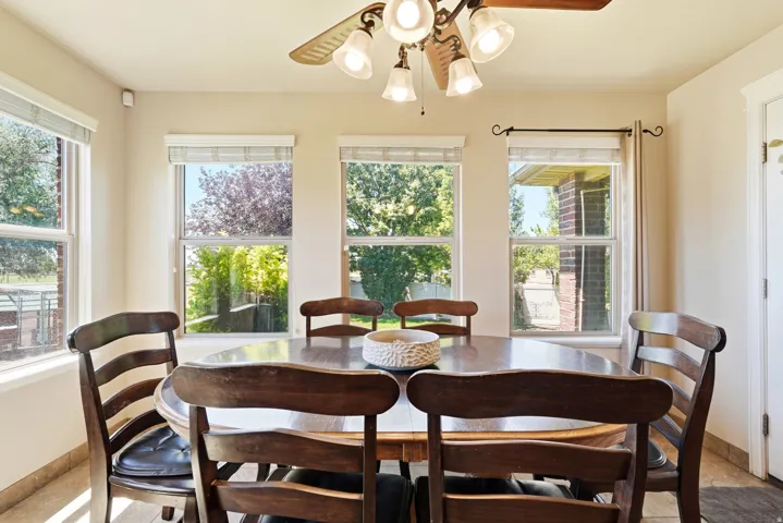 Dining area featuring multiple windows, a ceiling fan with integrated lighting, and tile flooring