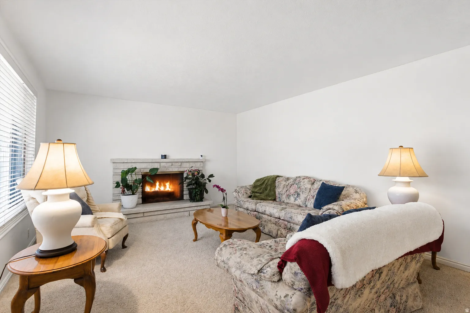 Living area featuring a stone-clad fireplace, light-toned carpeting, and white walls