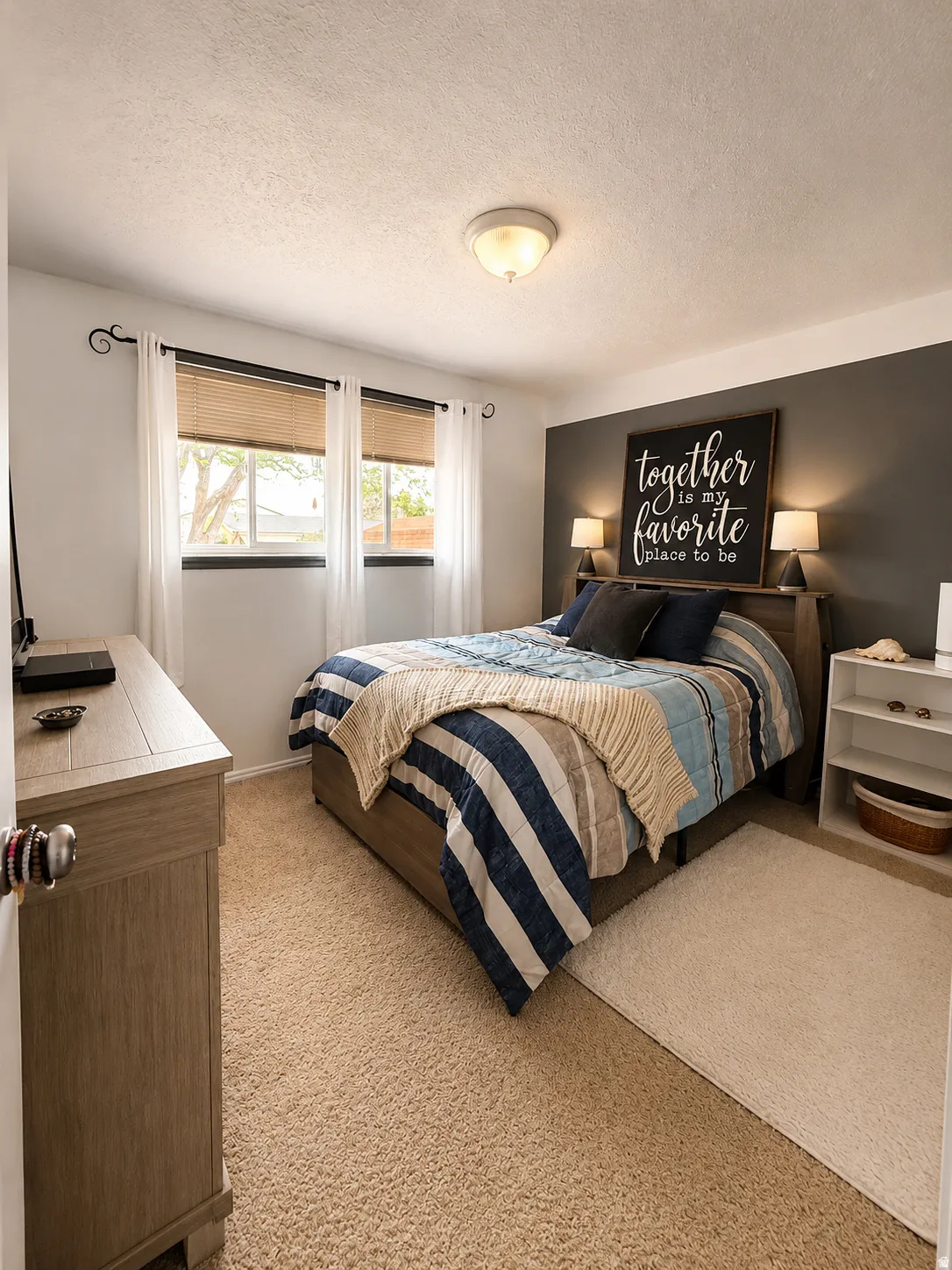 Carpeted room featuring a dark accent wall, two windows with blinds and curtains, and an overhead light fixture