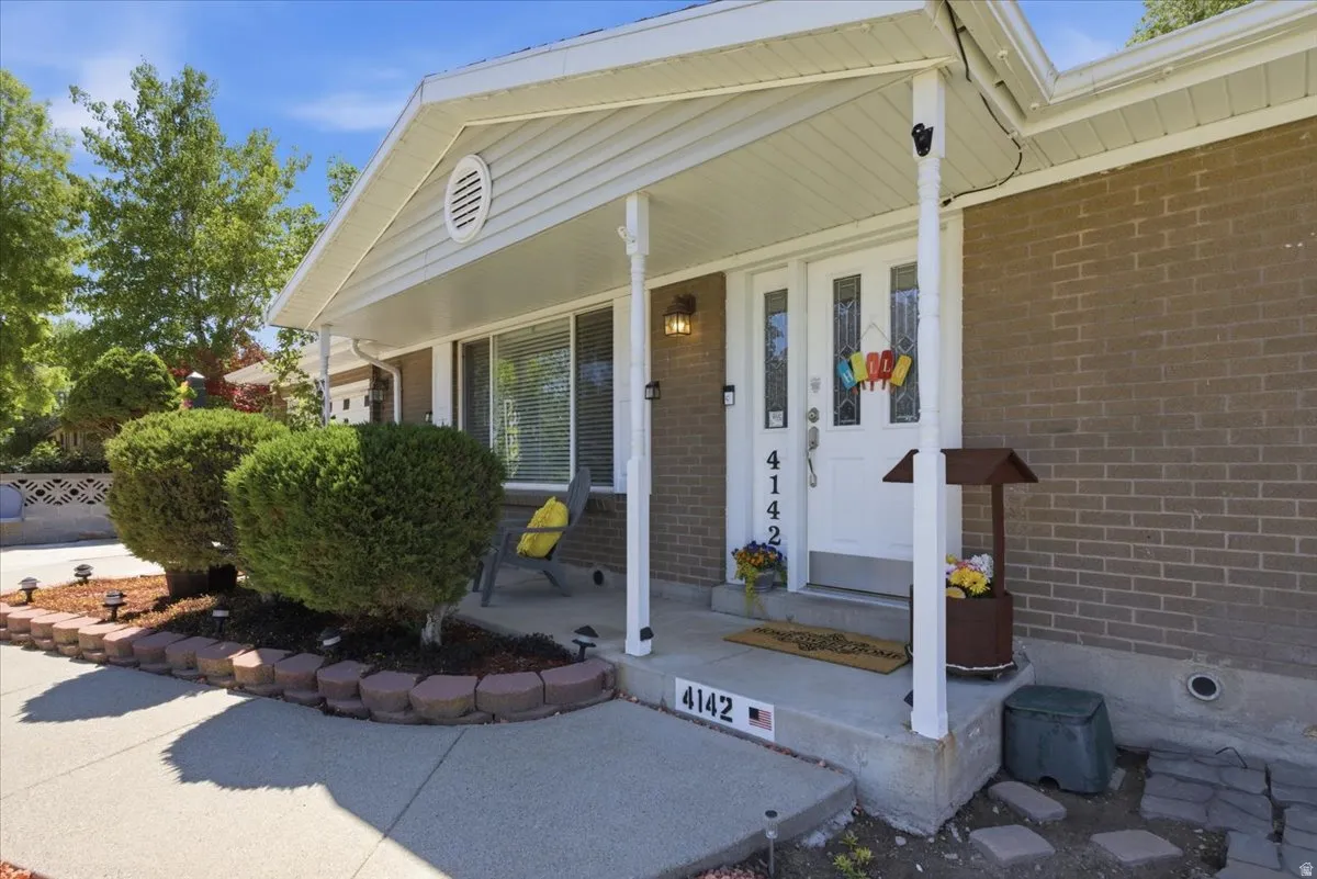 Brick exterior with a covered porch entry, white front door featuring decorative glass inserts, and an overhead porch light fixture