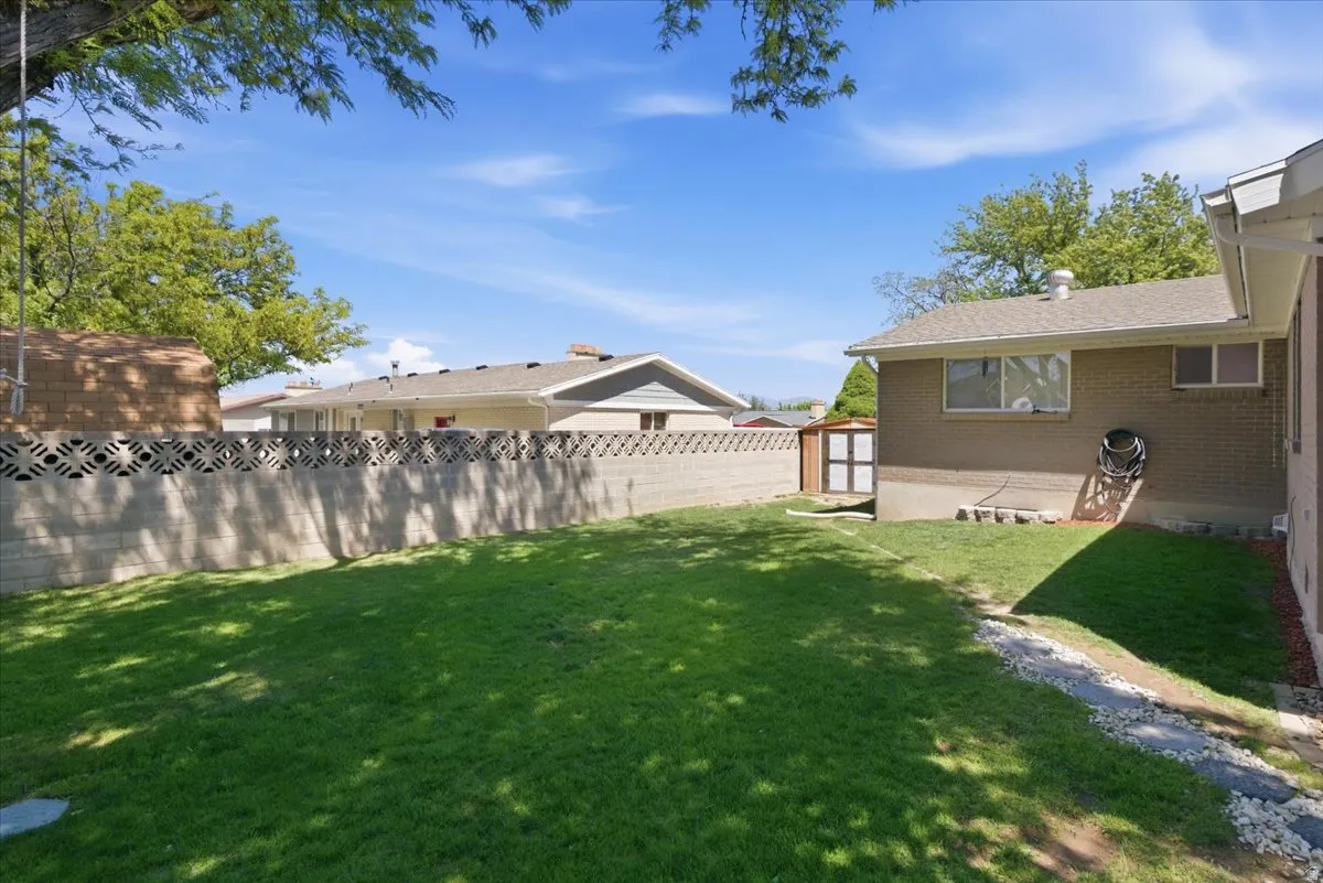 Expansive grassy yard area with a decorative concrete block privacy wall and a brick-sided exterior