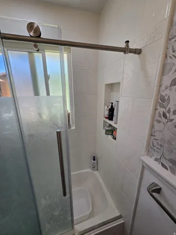 Shower-over-tub combination with sliding glass enclosure and built-in niche shelving